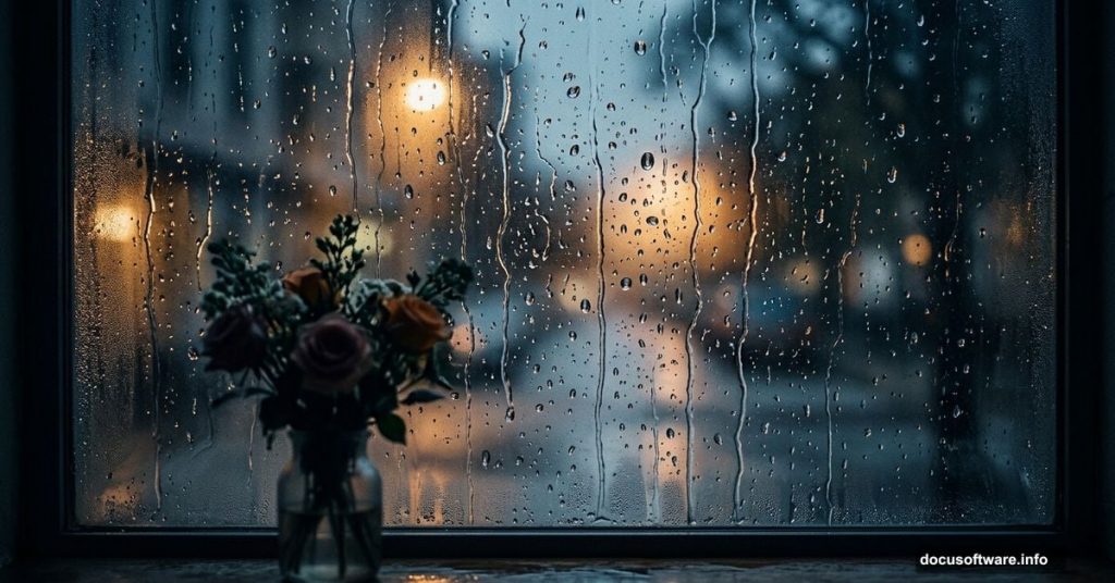 Moody rain-streaked window with flower vase on foggy sill
